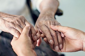 Pflegeperson von Zämespanne hält Hände einer Seniorin